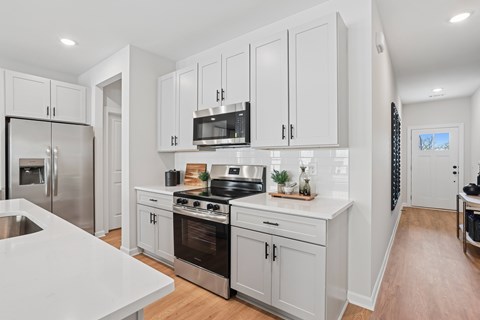 A modern kitchen with white cabinets and stainless steel appliances.