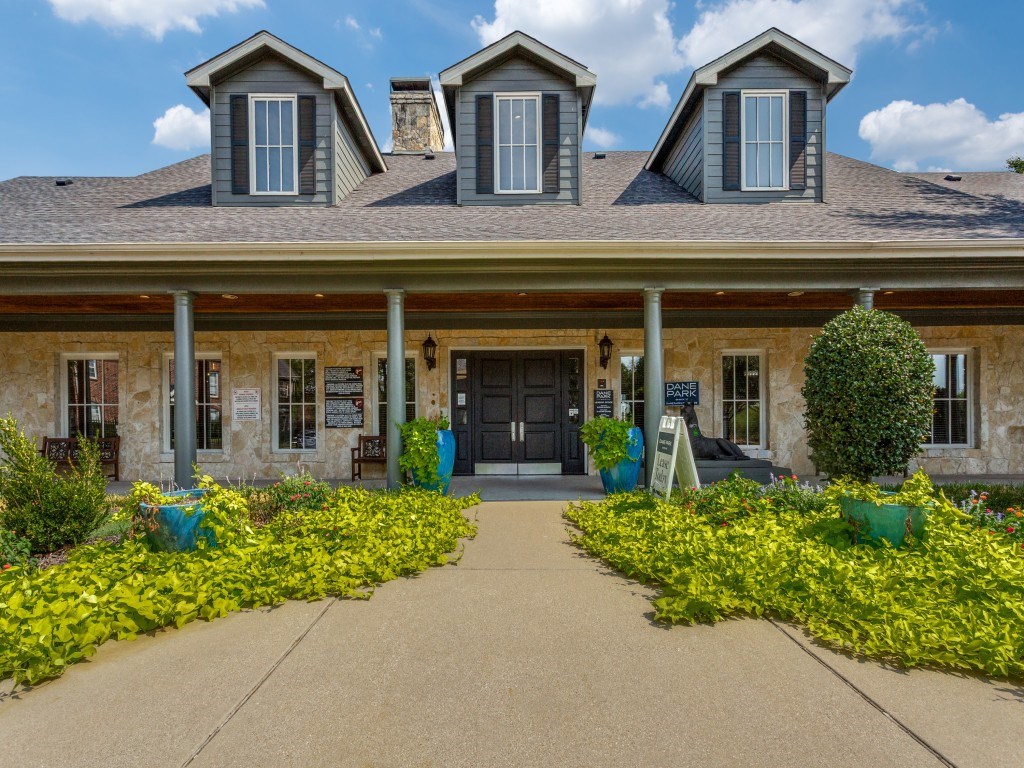 A building with a grey roof and a black door surrounded by yellow flowers.