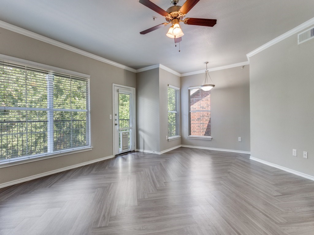 A room with a ceiling fan and light, hardwood floors, and a window with blinds.