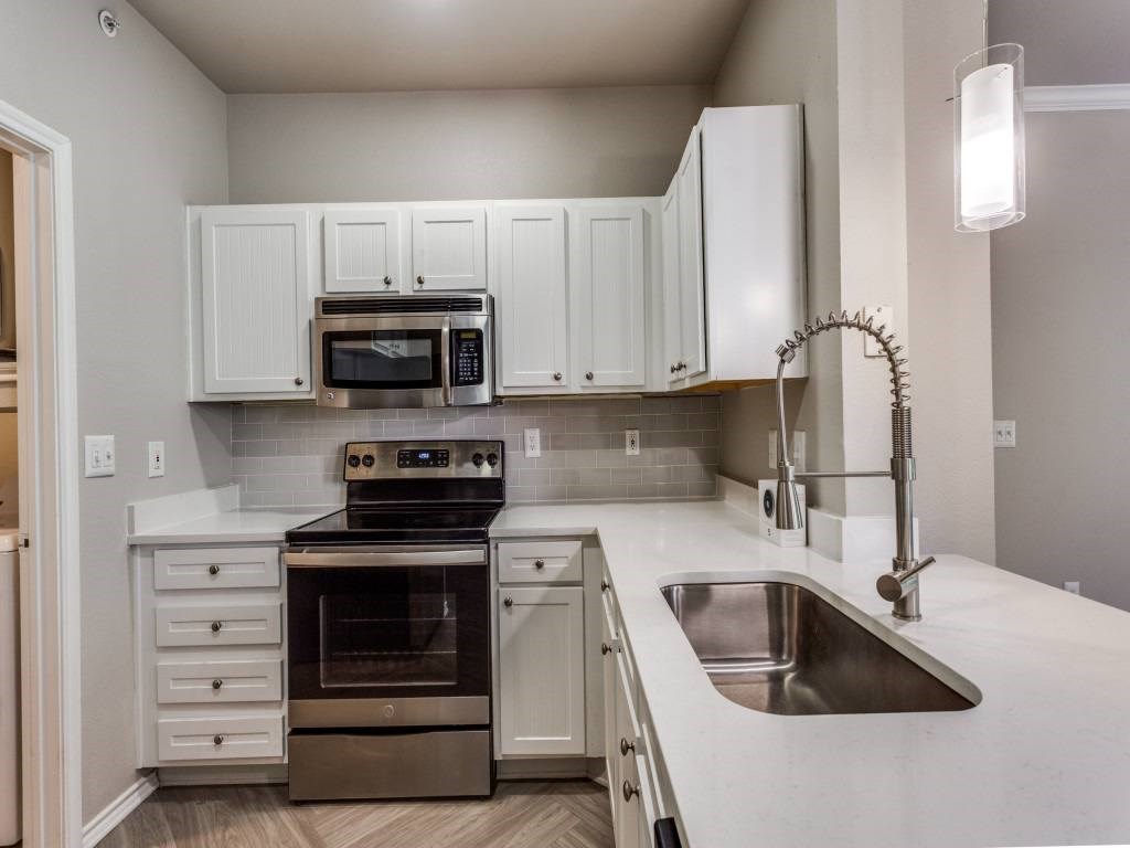 A kitchen with white cabinets and a stainless steel sink.