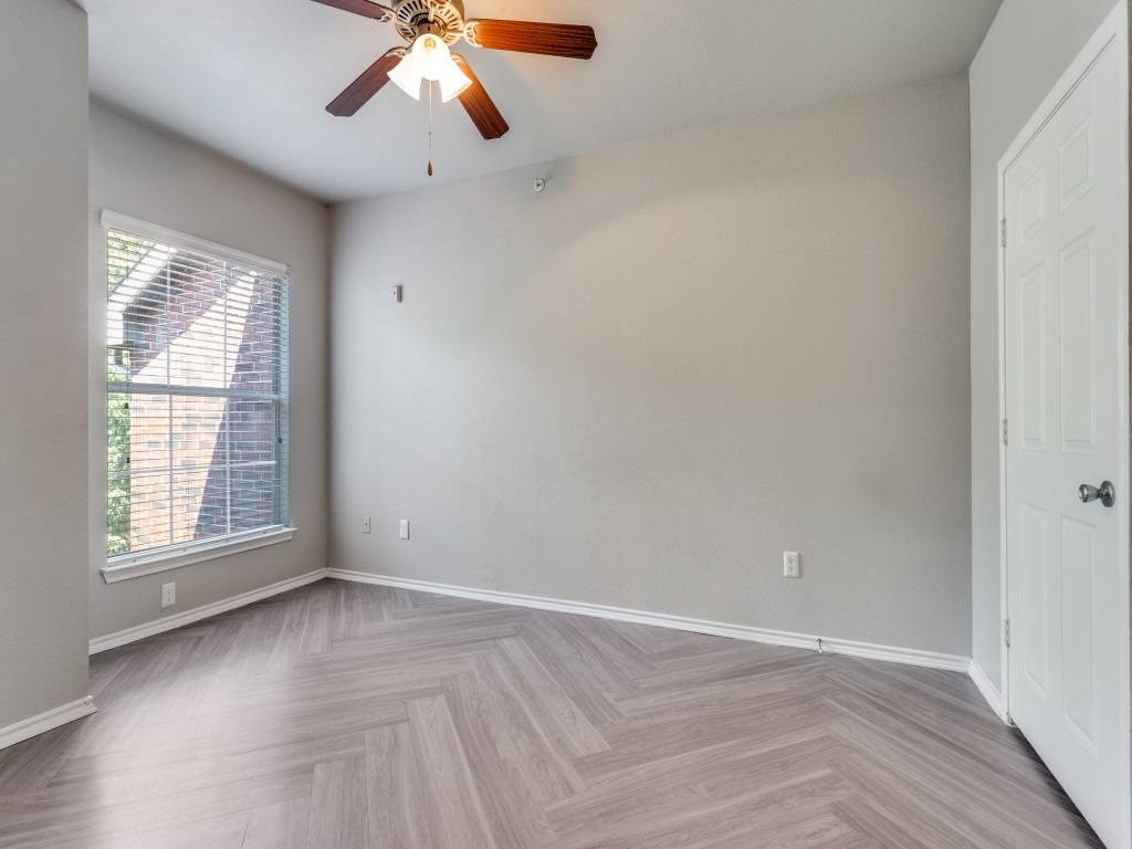 A room with a ceiling fan and a window with blinds.