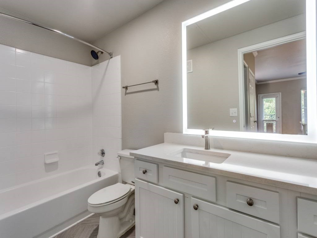A white bathroom with a toilet, sink, and mirror.