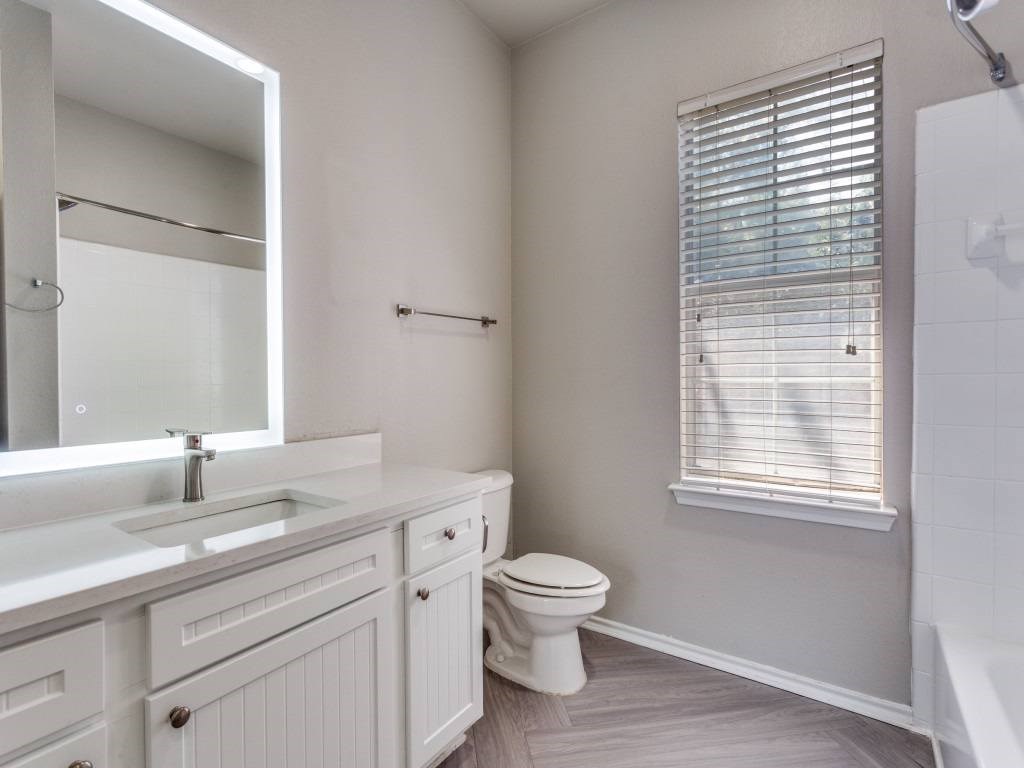 A white bathroom with a toilet, sink, and mirror.