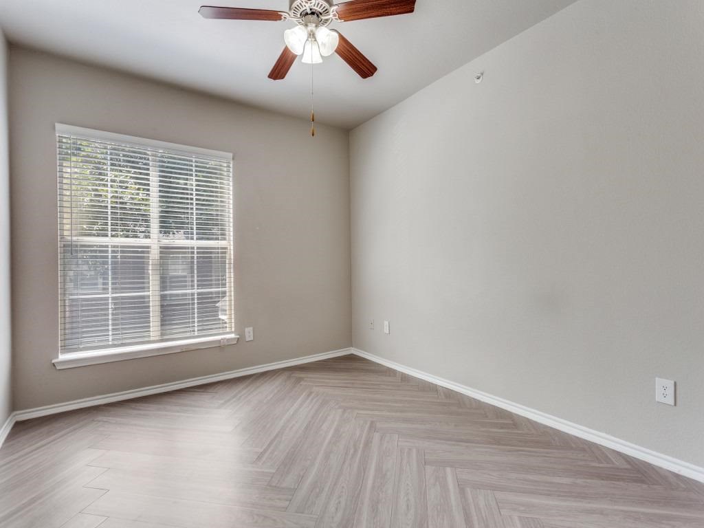 A room with a ceiling fan and a window with blinds.