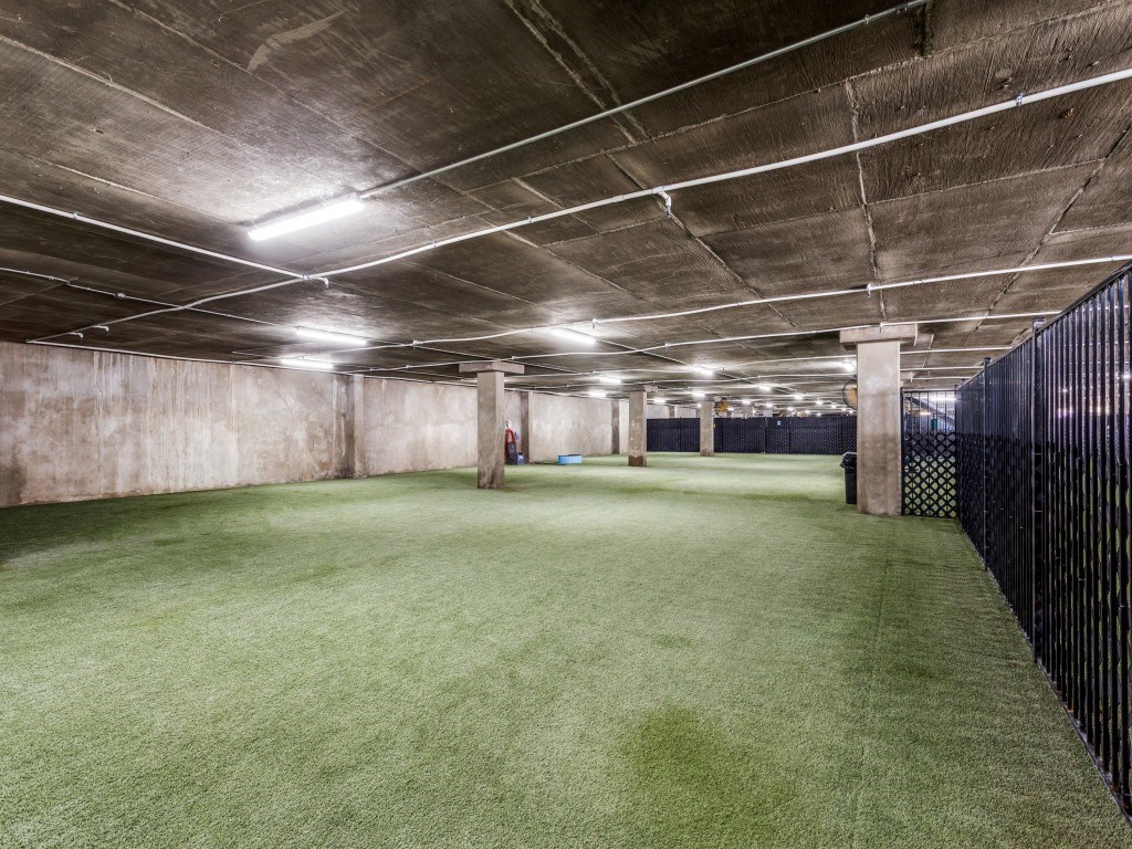 A large, empty parking garage with artificial grass.