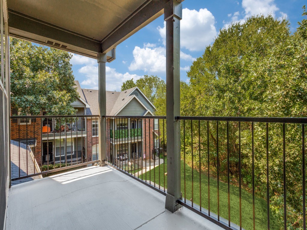 A balcony with a metal railing and a view of a building and trees.