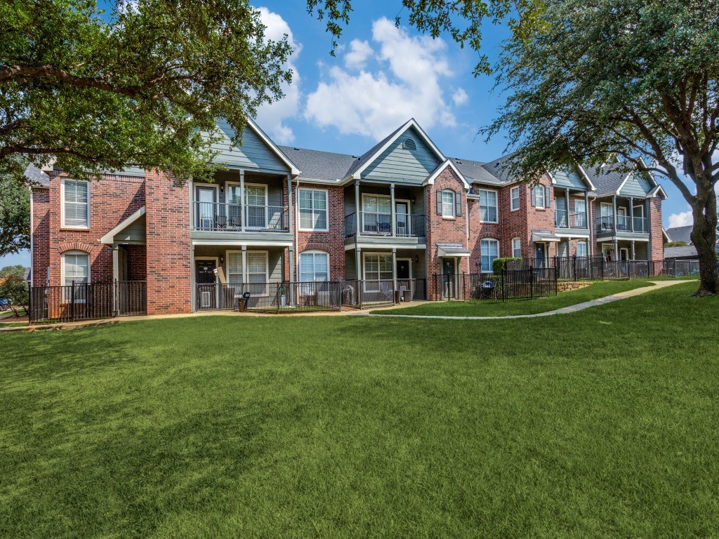 A large grassy area in front of a brick apartment building.