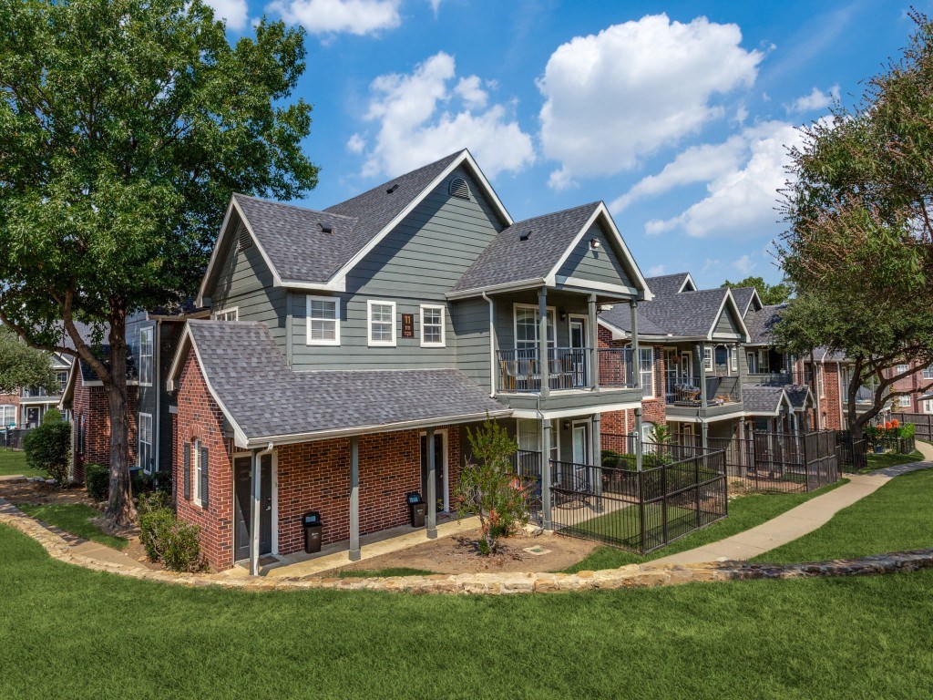 A large, two-story house with a grey roof and a brick foundation.