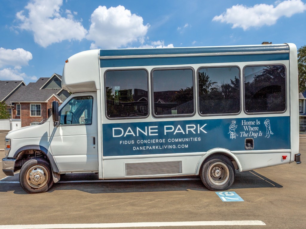 A white bus with the words Dane Park on the side is parked in a lot.