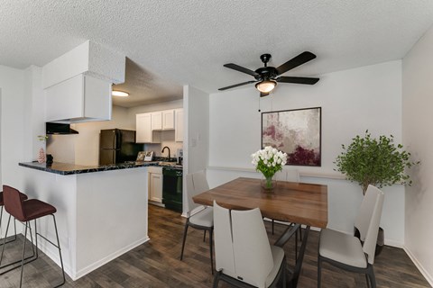 an open kitchen and dining area with a table and chairs and a ceiling fan