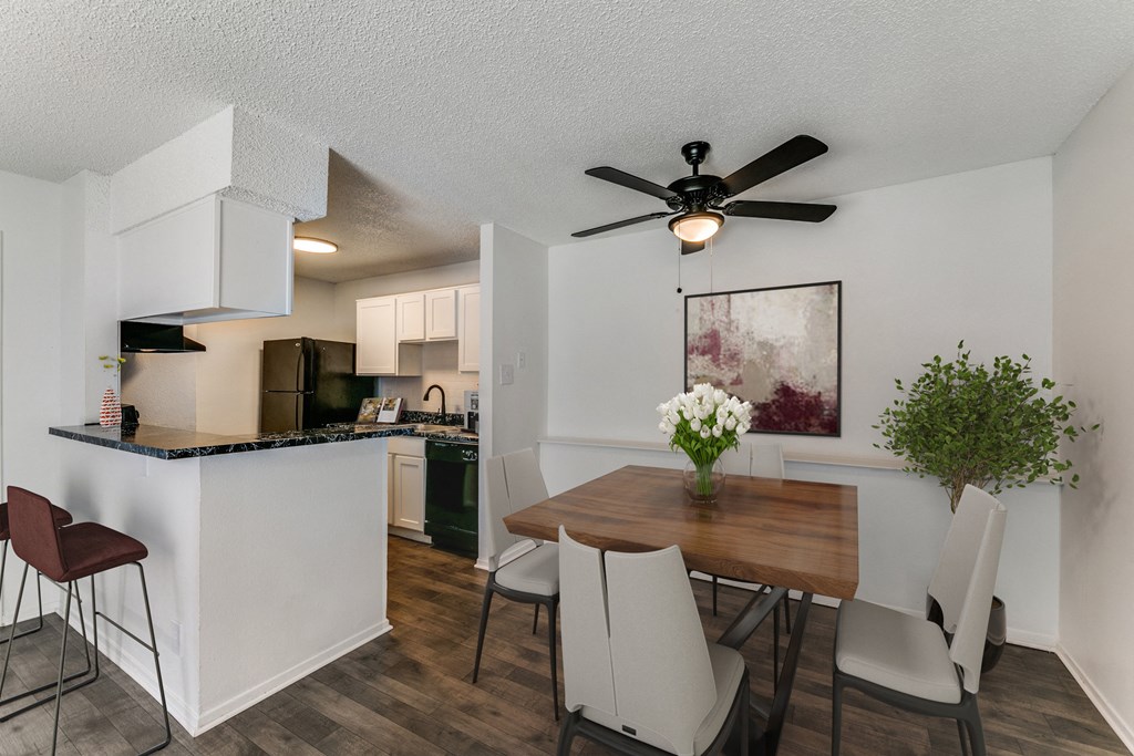 an open kitchen and dining area with a table and chairs and a ceiling fan