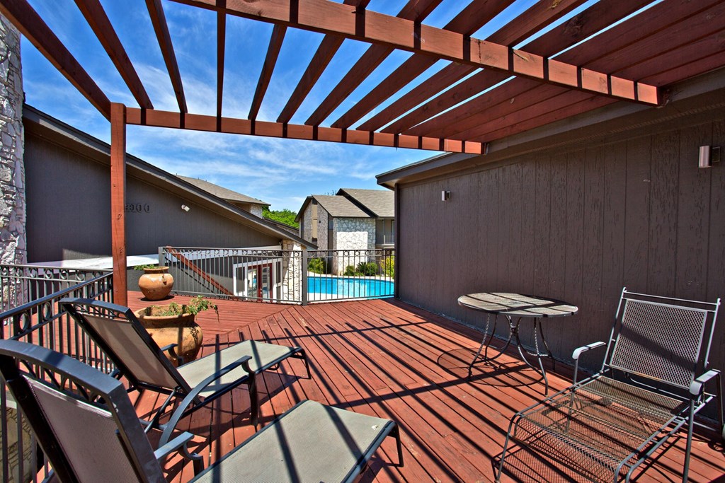 a covered deck with a pool and patio furniture