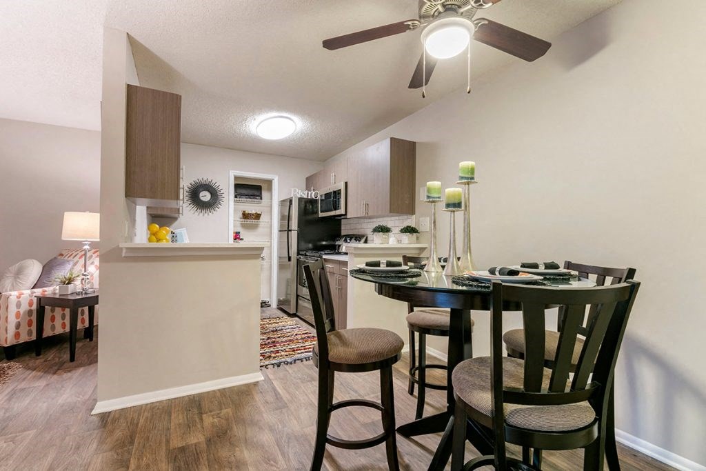 a dining area with a table and chairs and a kitchen in the background