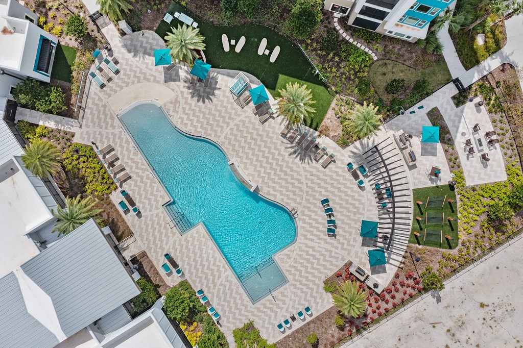 A pool surrounded by a patio and a garden.