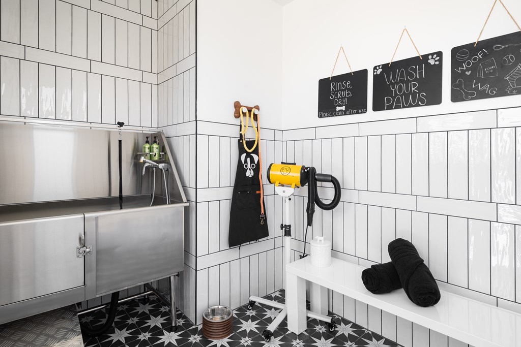 A bathroom with a white tiled wall and a black and white floor.