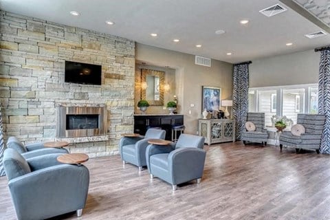 a living room with blue chairs and a stone fireplace