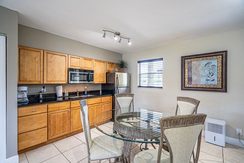 a dining room with a glass table and chairs and a kitchen