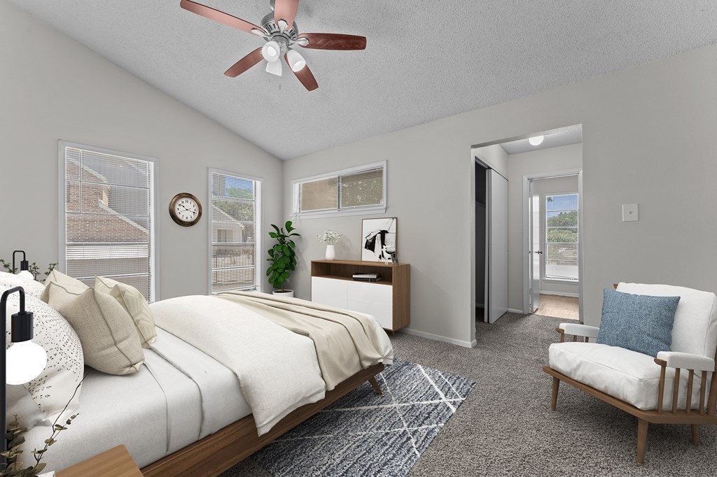 A bedroom with a bed, chair, and a ceiling fan.