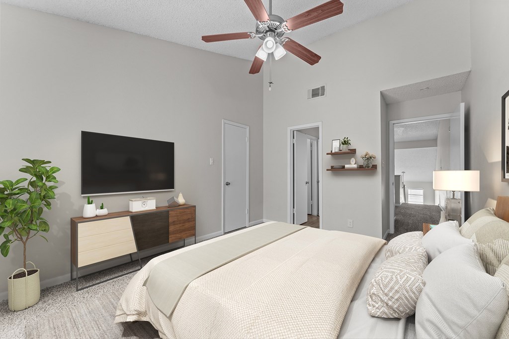 A bedroom with a large bed, a television, and a ceiling fan.