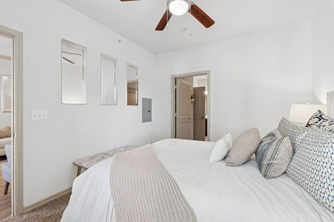 A bedroom with a large bed and a ceiling fan.