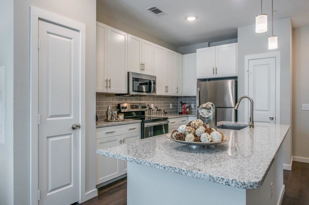 a kitchen with white cabinets and a granite counter top