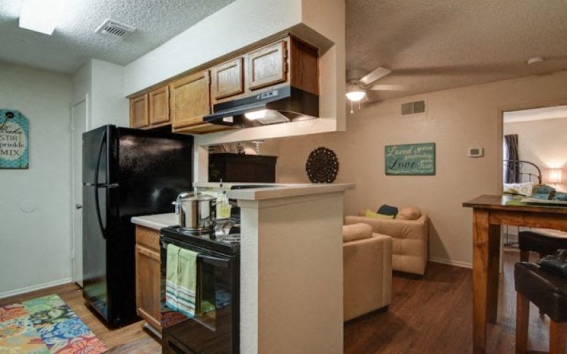 a kitchen and living room with a black refrigerator and stove