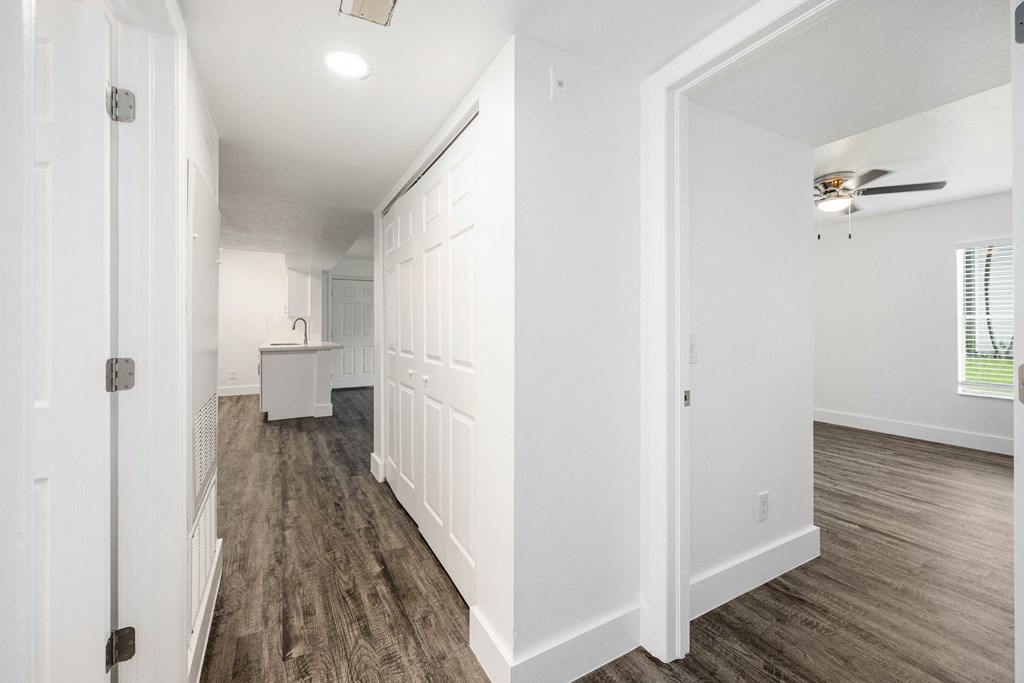 a renovated living room and kitchen with white walls and wood flooring