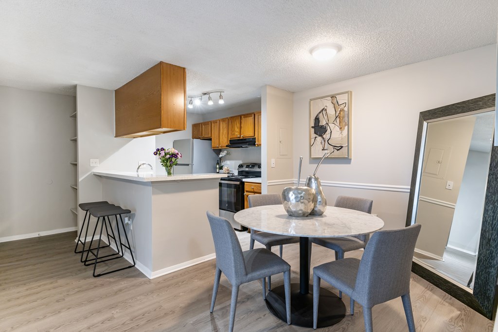 A kitchen with a bar and a dining table with chairs.