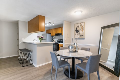 A kitchen with a bar and a dining table with chairs.