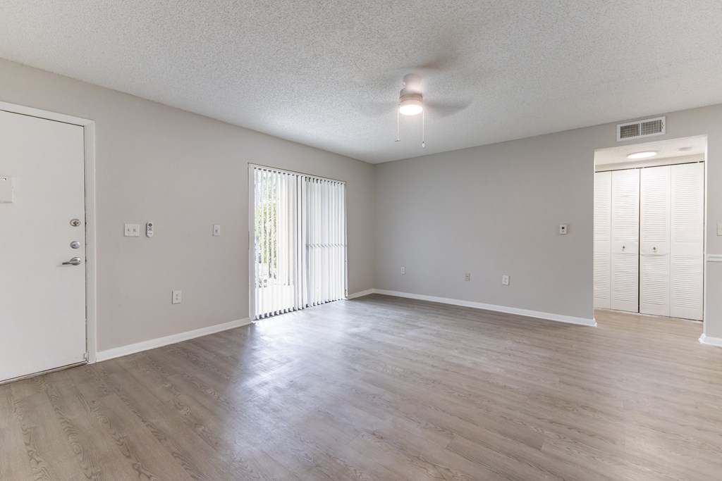 A spacious room with a sliding glass door and a ceiling fan.