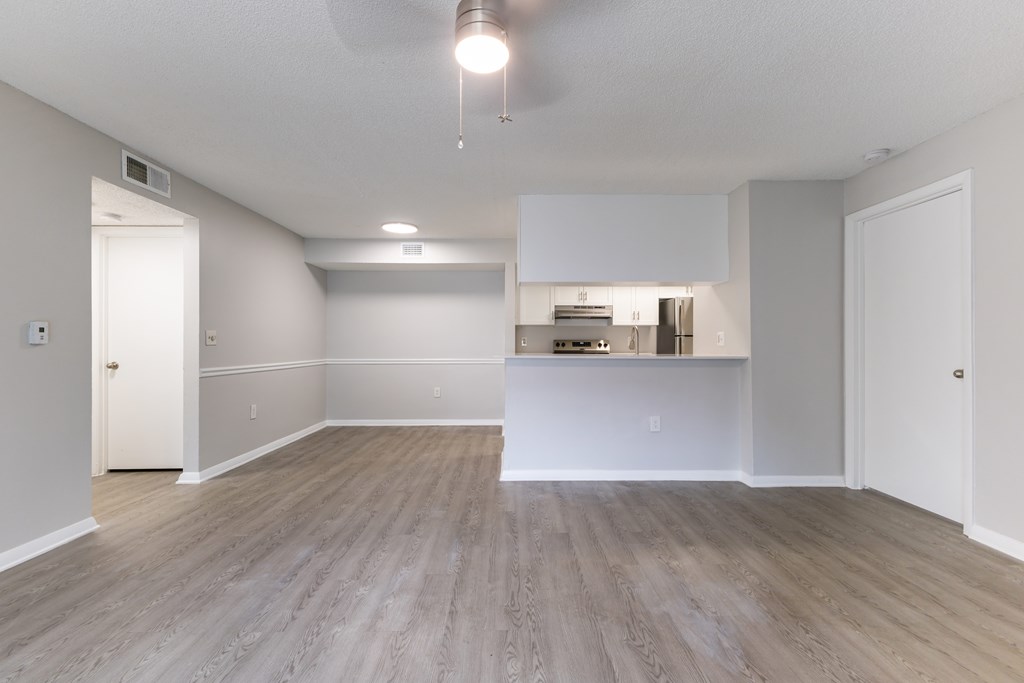 A spacious room with a kitchenette in the background.