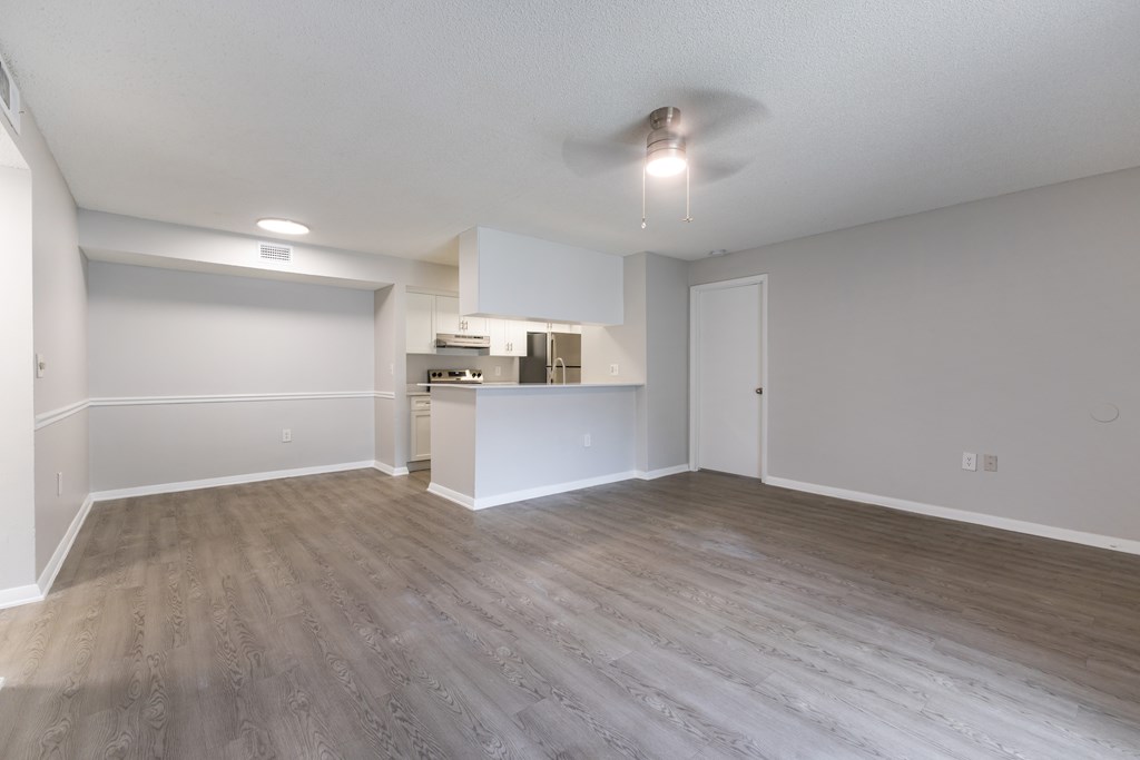 A spacious room with wooden flooring and a ceiling fan.