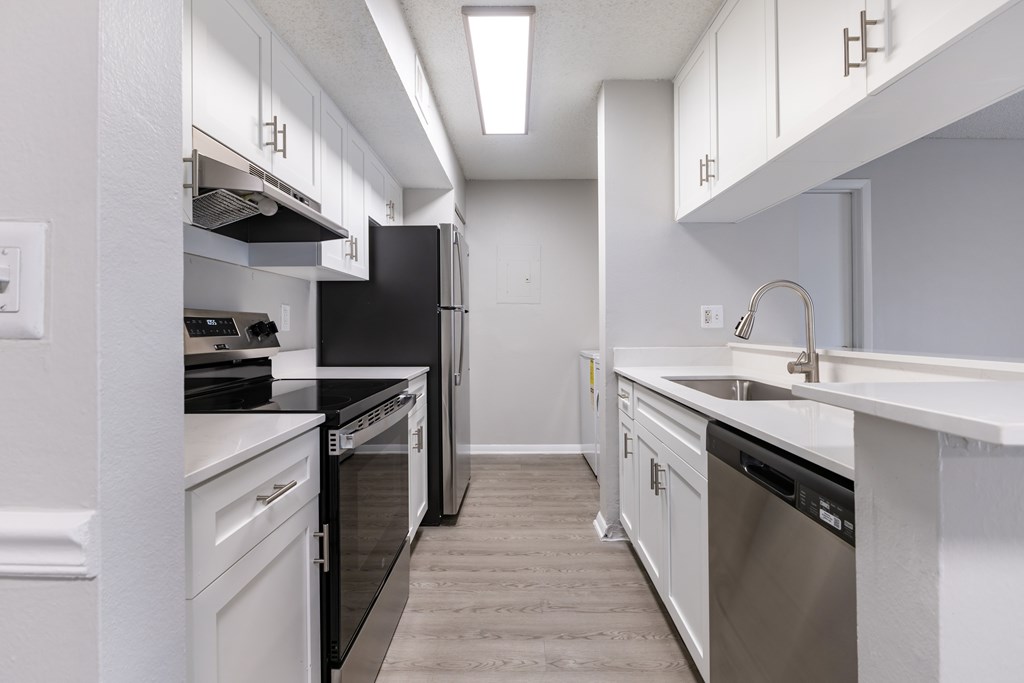 A modern kitchen with black appliances and white cabinets.