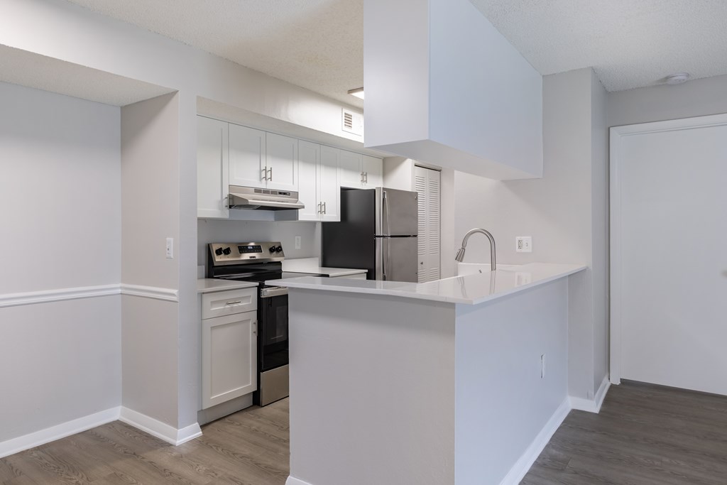 A kitchen with white cabinets and a black refrigerator.