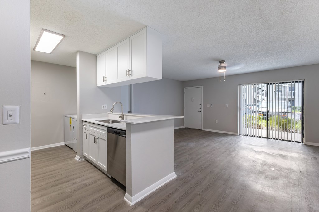 A kitchen with white cabinets and a wooden floor.