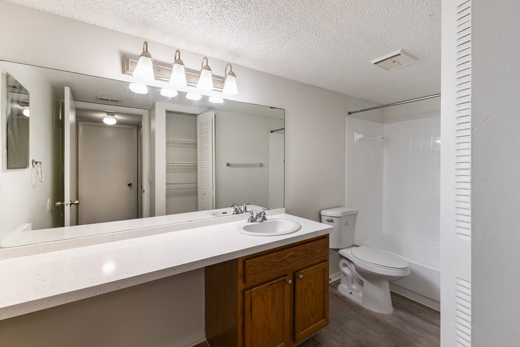 A bathroom with a white countertop and a wooden cabinet.