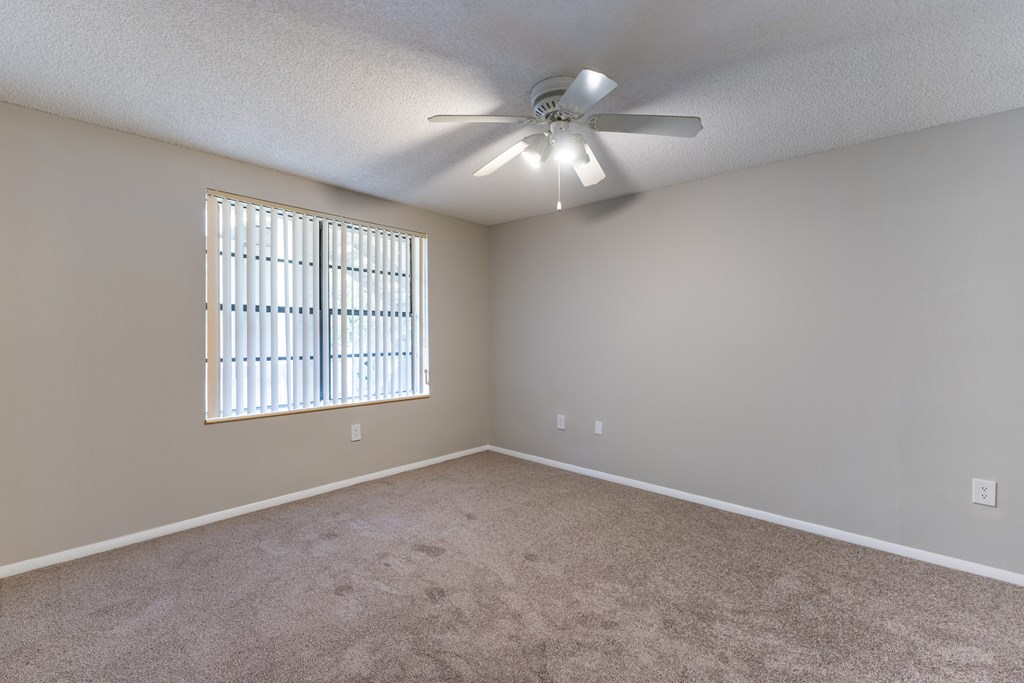 A room with a ceiling fan and a window with blinds.