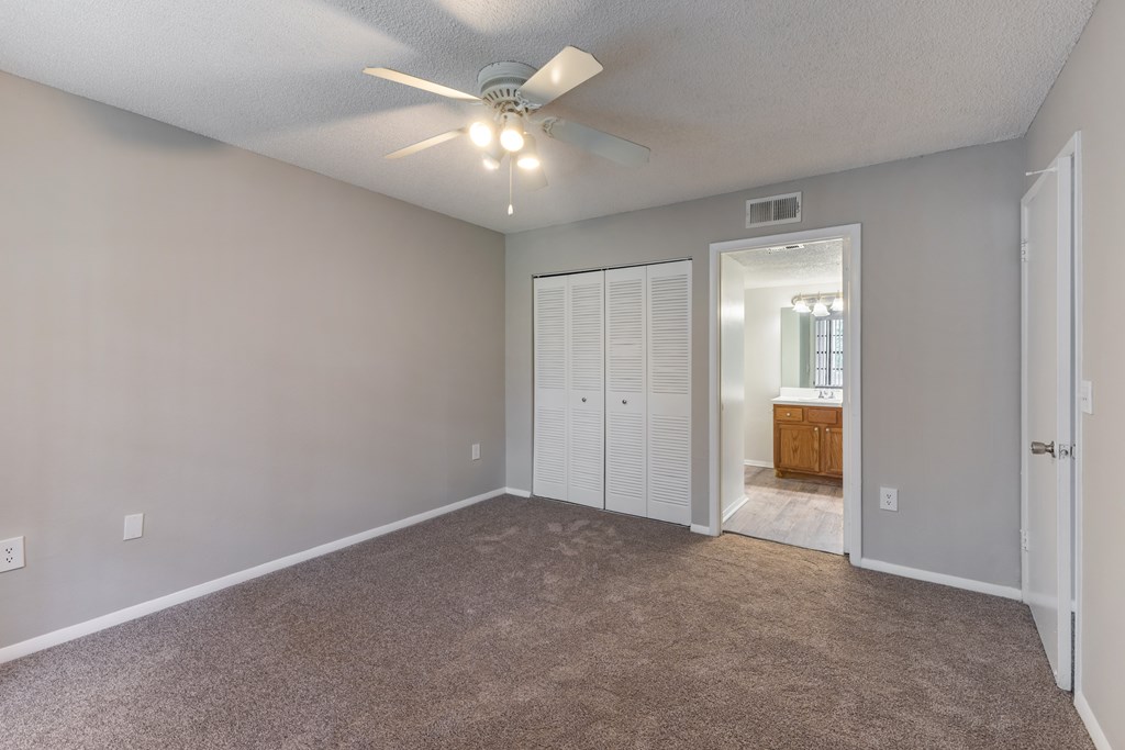A room with a ceiling fan and carpeted floor.
