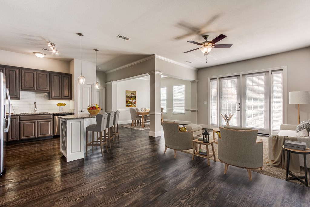 a living room with a kitchen and a ceiling fan