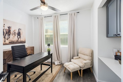 A room with a black desk and a chair.