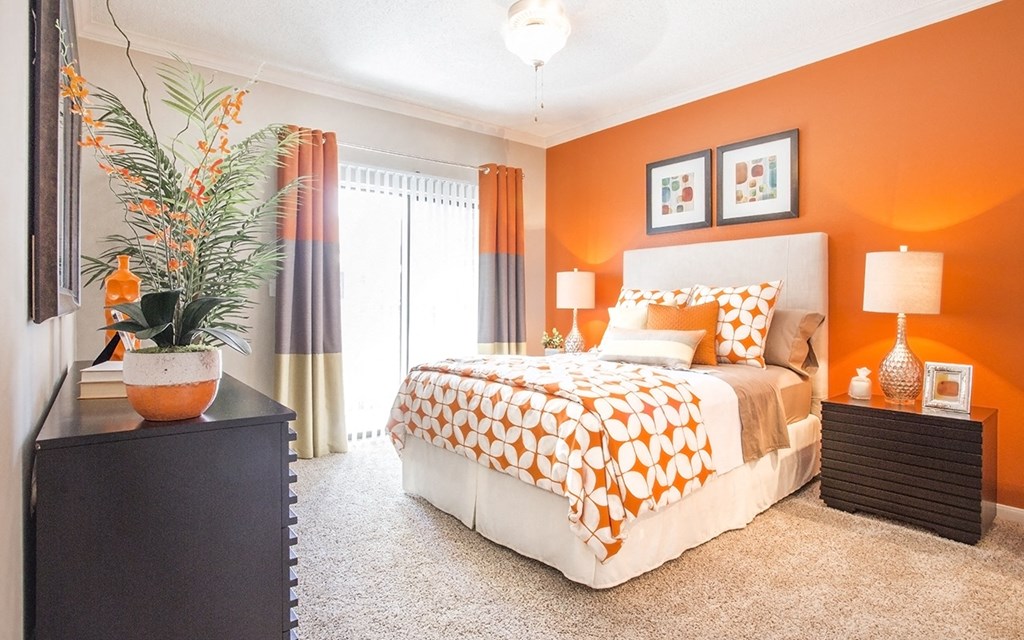a bedroom with an orange accent wall and a bed