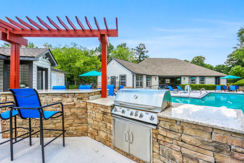 our yard has a barbecue grill and a pool with a house in the background