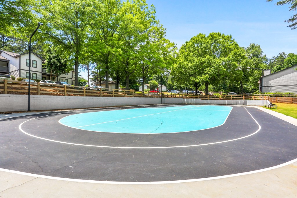 the basketball court in the backyard of a house with trees