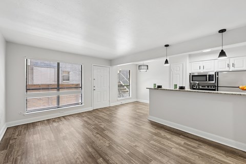 A kitchen with a white counter and wooden floors.