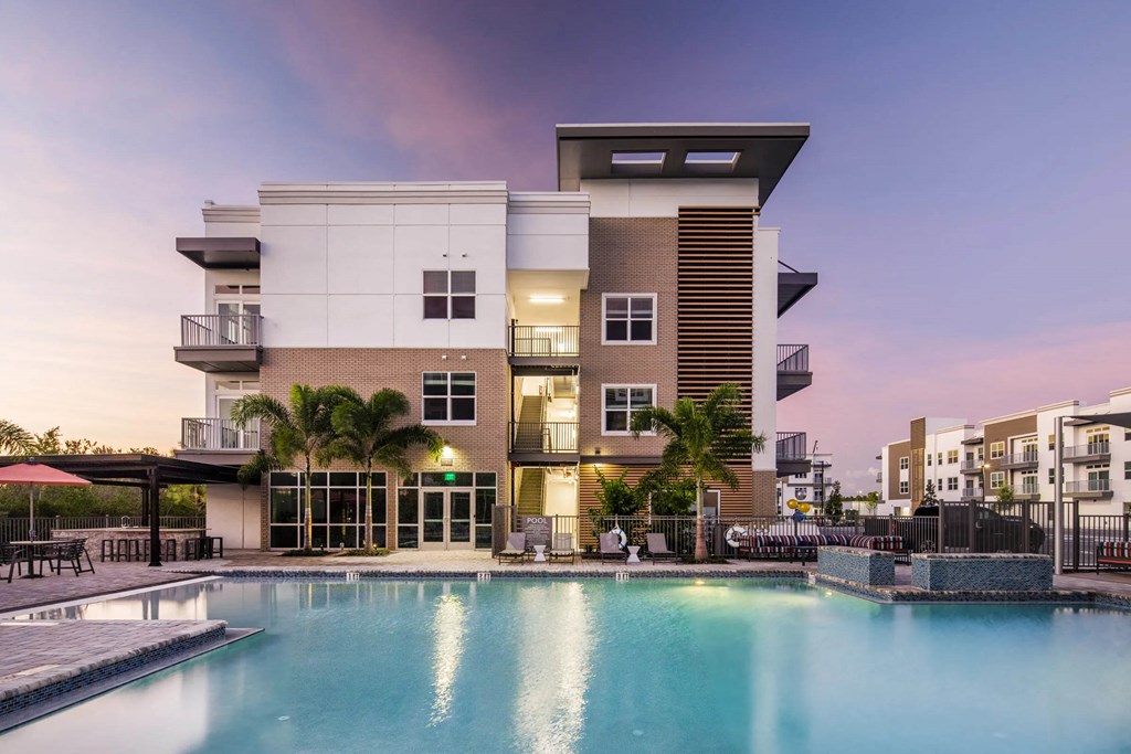 a luxury apartment building with a pool at dusk