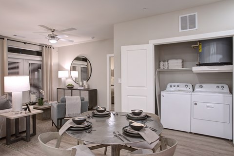A modern dining room with a table set for four and a washer and dryer in the background.