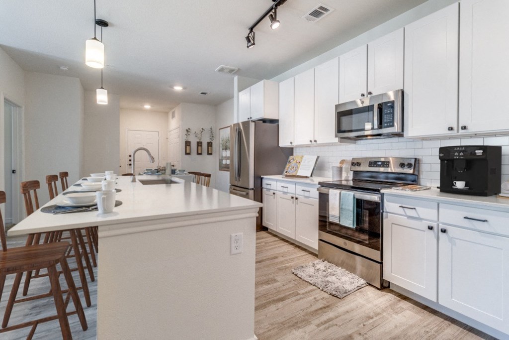 a large kitchen with white cabinets and stainless steel appliances
