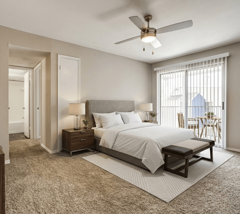 A bedroom with a large bed, a ceiling fan, and a window with blinds.