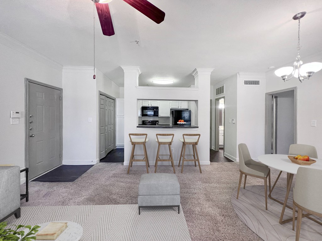 a living room with a dining area and a kitchen with bar stools
