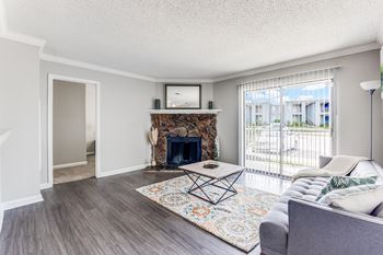 A living room with a grey couch, a fireplace, and a rug.